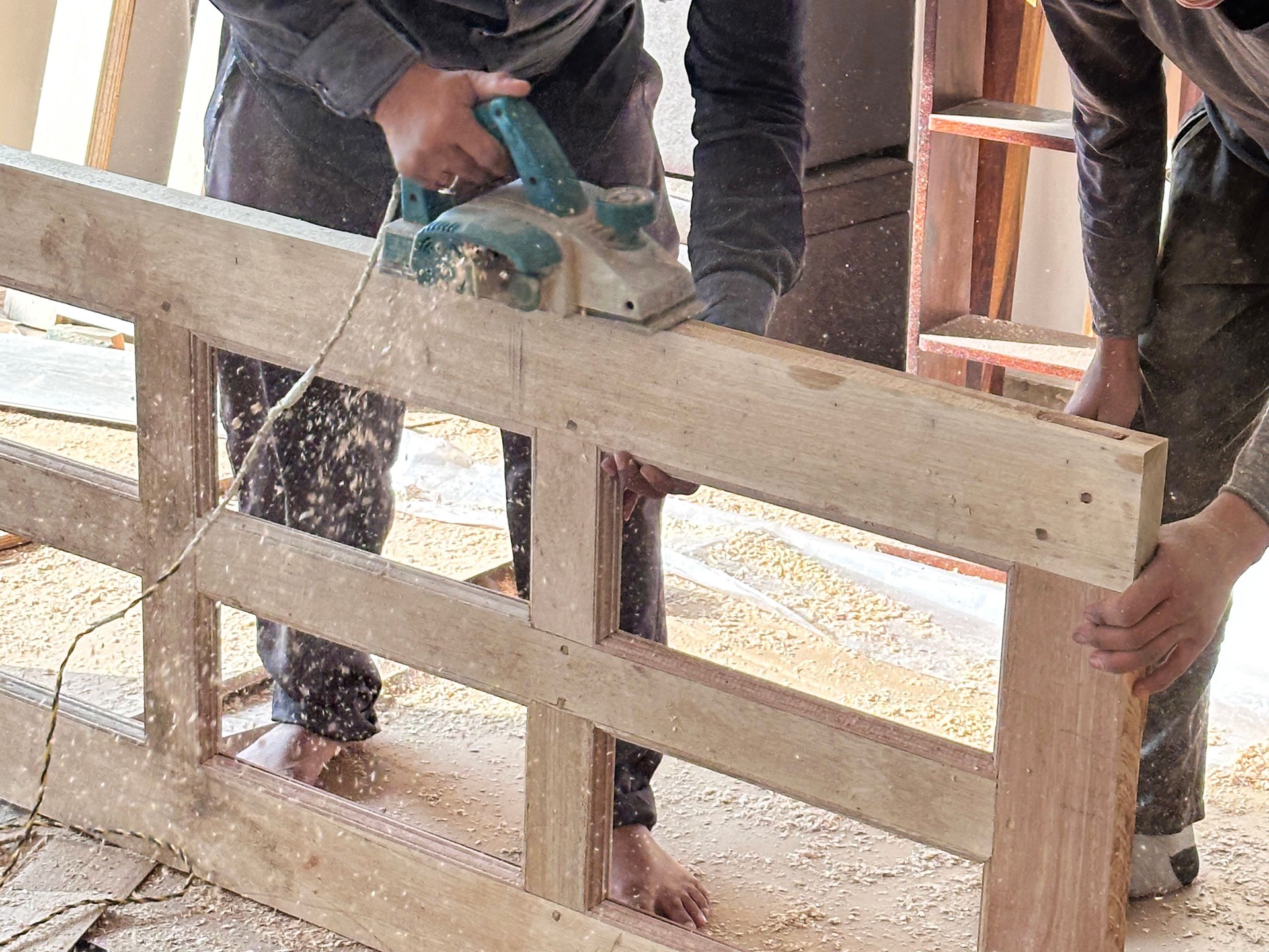 Image of skilled carpenter planing wooden door / precision craftsmanship, interior workshop, shaping wood, internal design, door installation