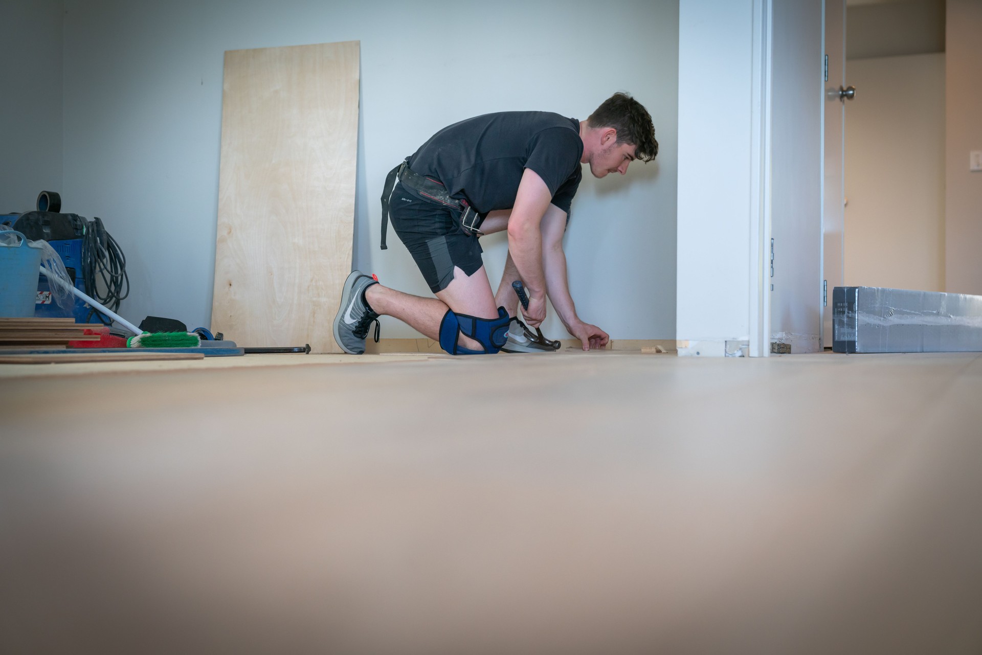Tradesman laying new wooden floor in home.